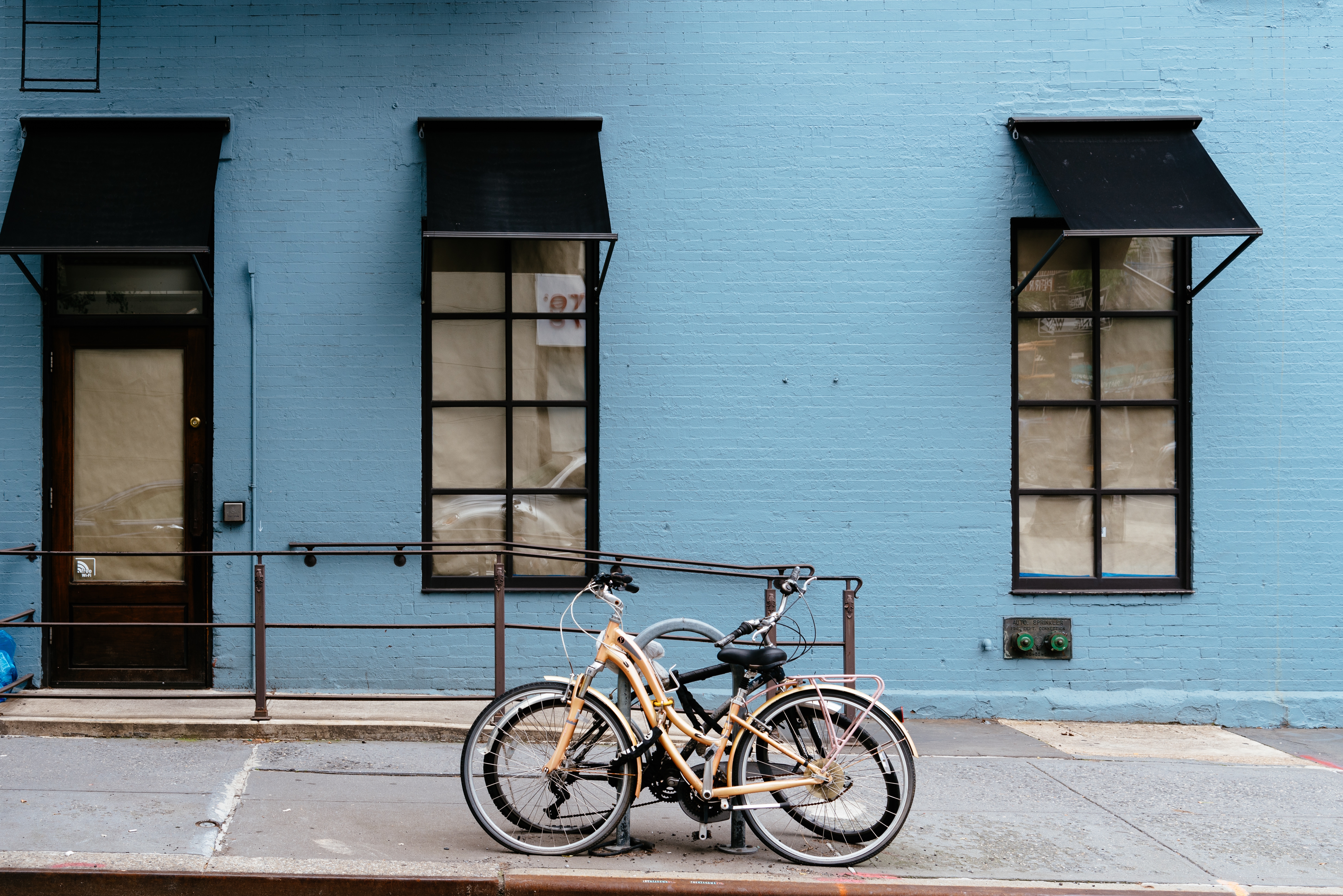 Bicycles parked besides old apartment building with brick facade painted in blue at Greenwich Villag