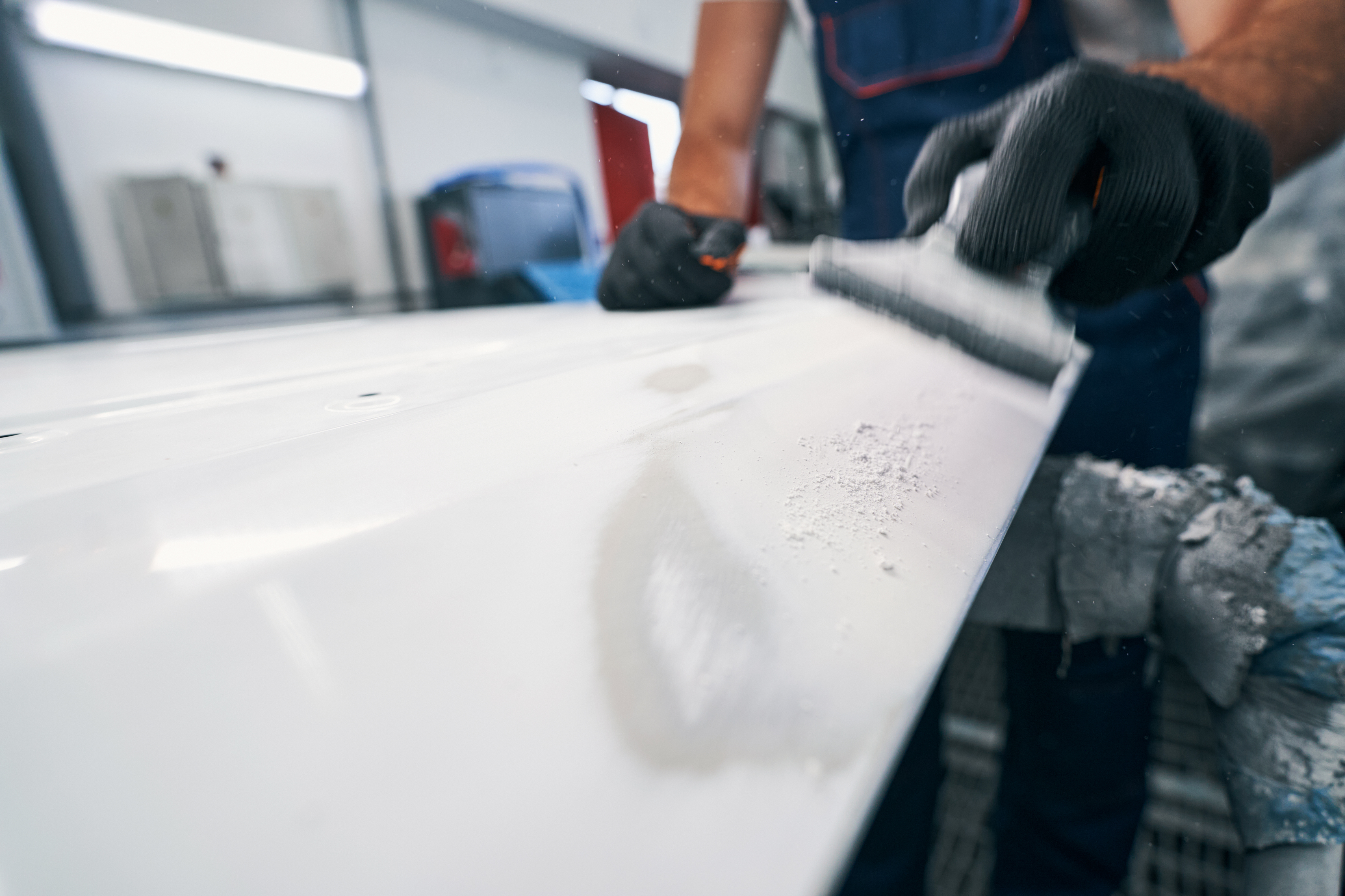 Hand sander removing white paint from metal