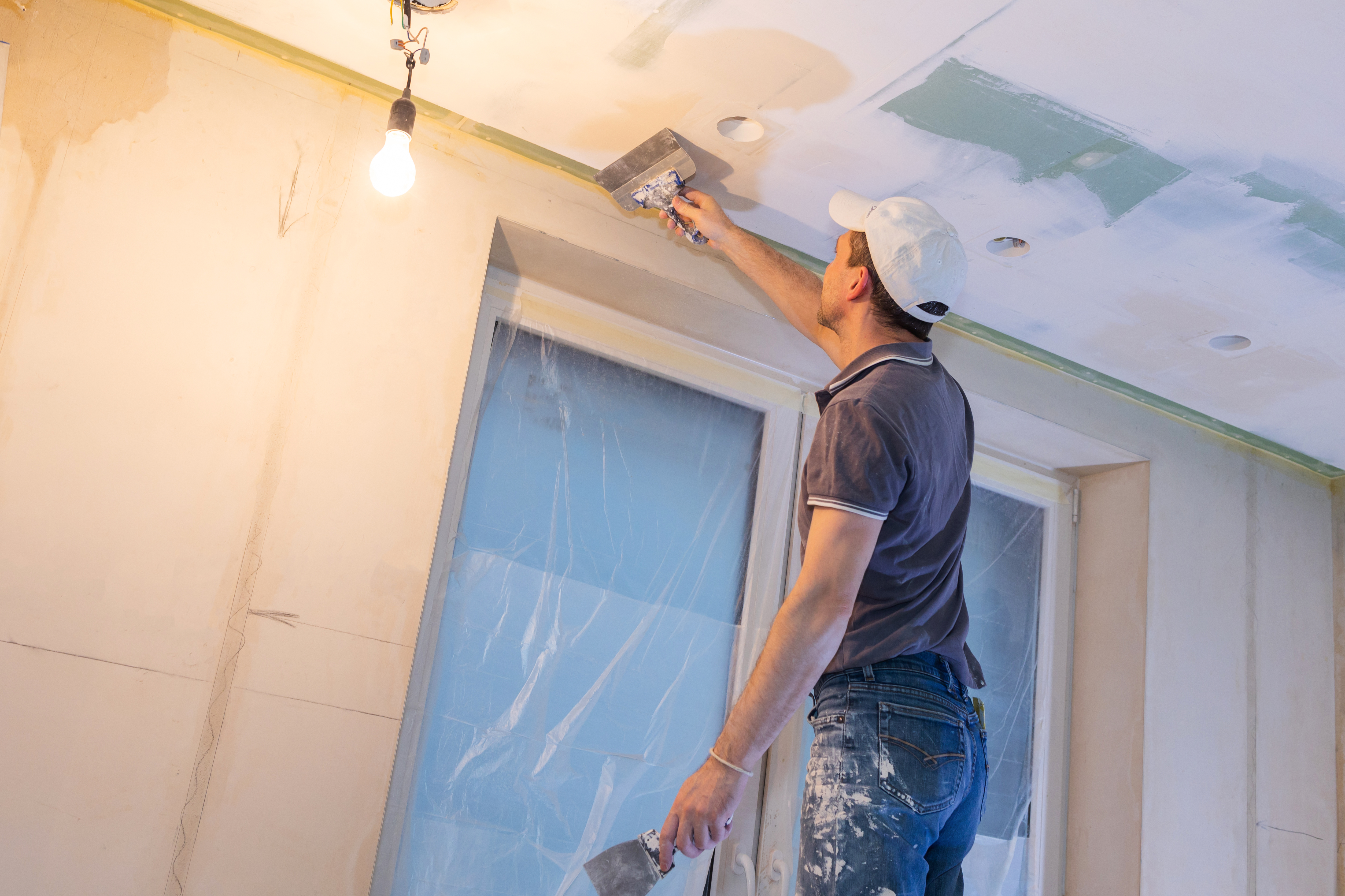 Worker make repairs in new apartment. Man plaster walls and ceilings