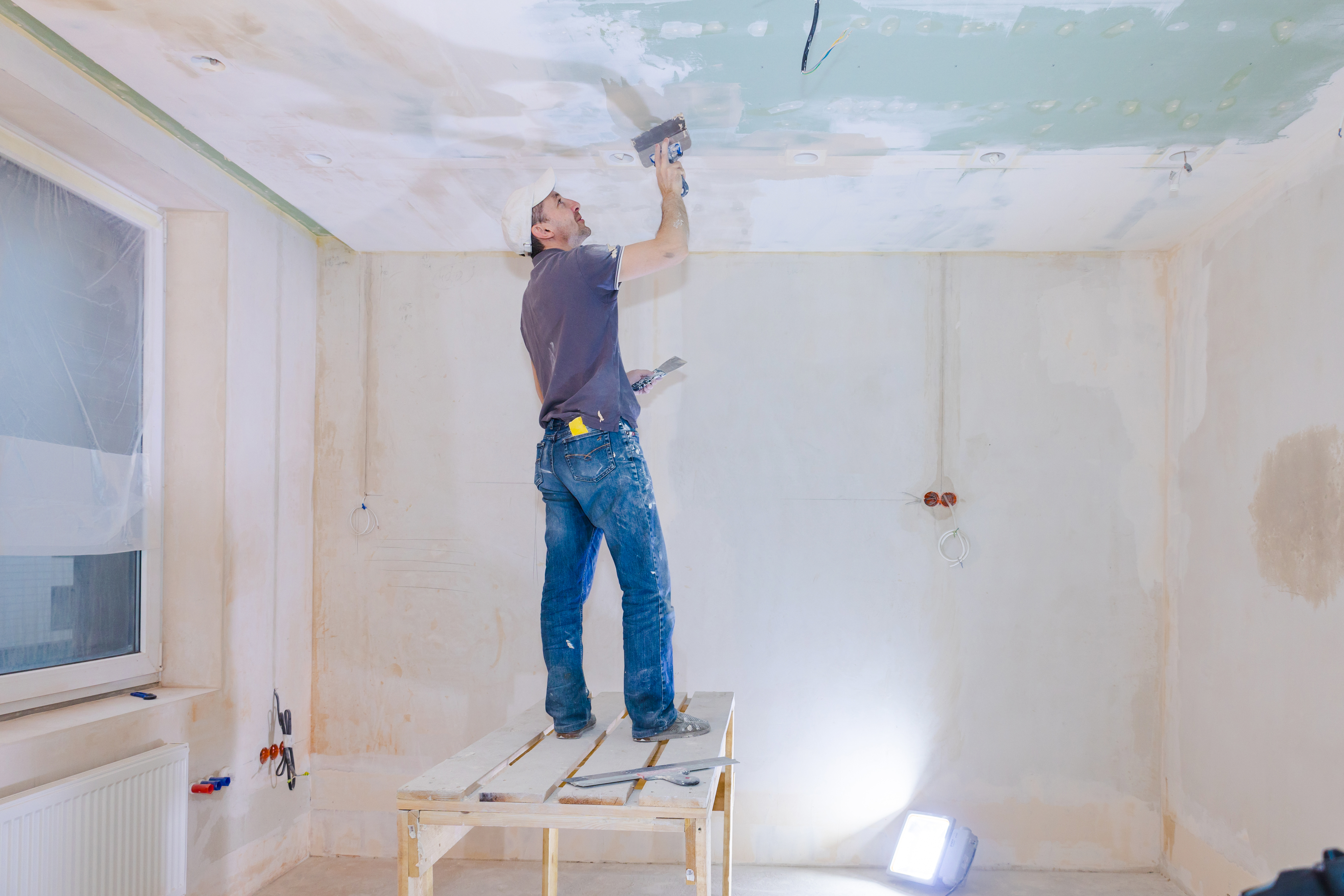 Worker make repairs in new apartment. Man plaster walls and ceilings